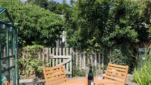Une table en bois, deux chaises, une bouteille de vin et un verre posés dessus.