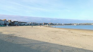 Une vaste plage de sable avec des bâtiments en arrière-plan.