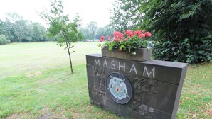 A sign with the name "MASHAM" and a decorative emblem.
