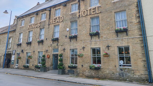 A stone building with the sign "King's Head Hotel" and "Pub Dining Rooms" indicating it is a pub and hotel.