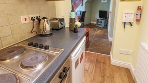 A kitchen with a stove, toaster, kettle, and a fire blanket on the wall.