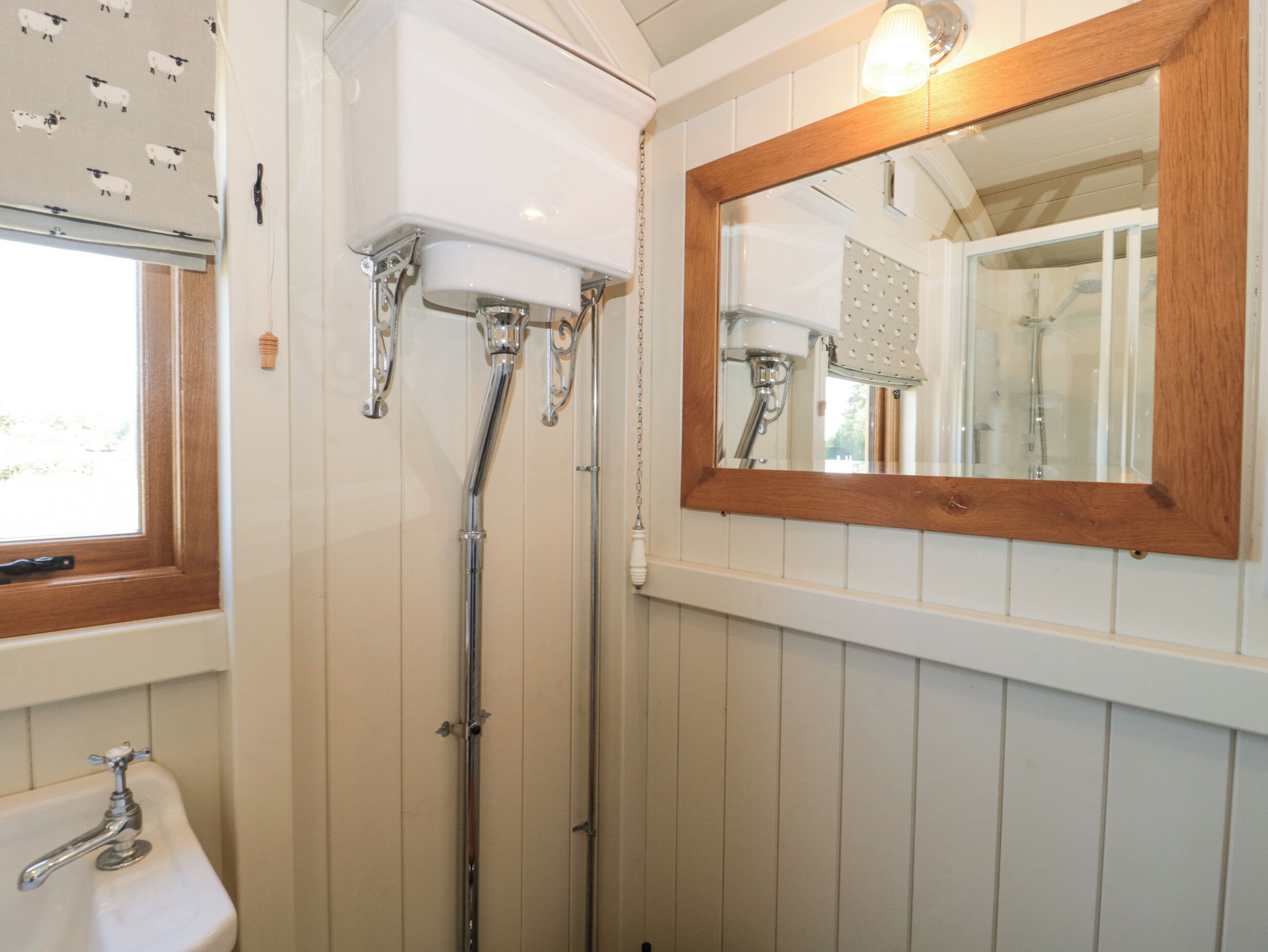 A bathroom with a white sink, a shower with a chrome faucet, and a wooden-framed mirror.