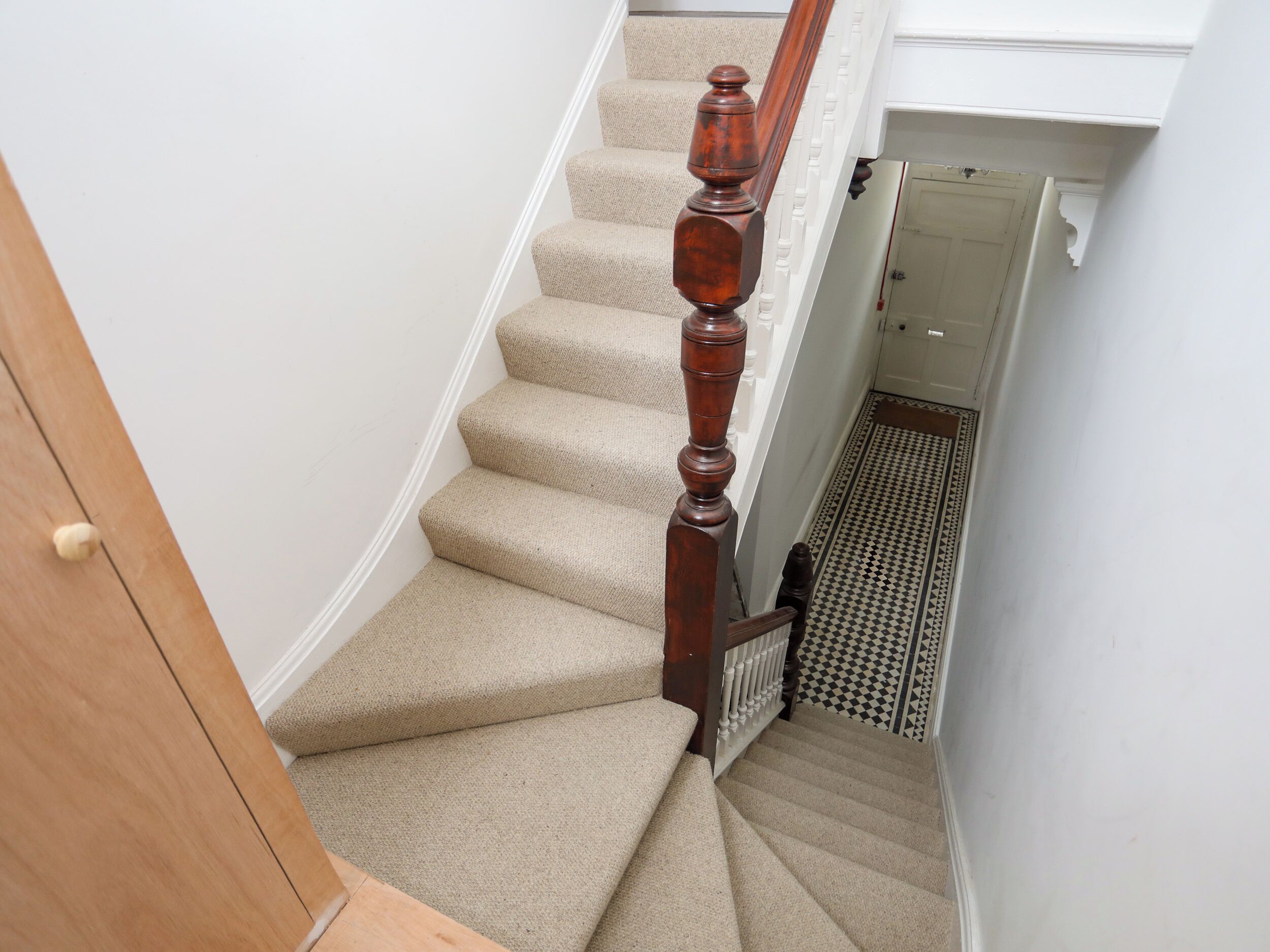 A carpeted staircase with wooden balusters and a white door at the top.