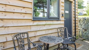 A wooden cabin with a window, a door labeled "CHESTER", and two metal chairs and a table outside. - Chester (Wrexham)