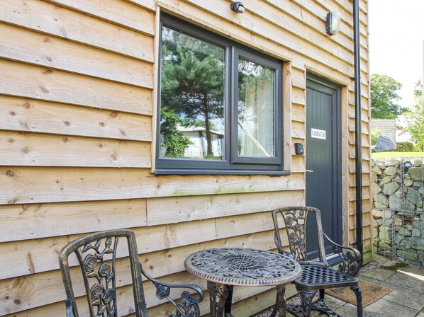 A wooden cabin with a window, a door labeled "CHESTER", and two metal chairs and a table outside. - Chester (Wrexham)