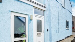 Une maison bleue avec une porte et des fenêtres blanches.