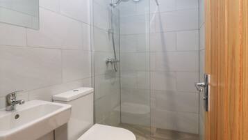 A modern bathroom with a toilet, sink, and glass-enclosed shower.