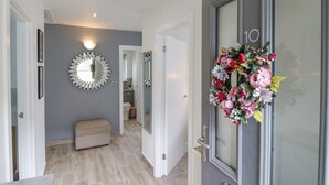 A hallway with a grey door, a mirror, and a floral wreath. - Jasmine Cottage (Herne Bay)
