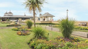 A garden with a gazebo, palm tree, and flowers. - Jasmine Cottage (Herne Bay)