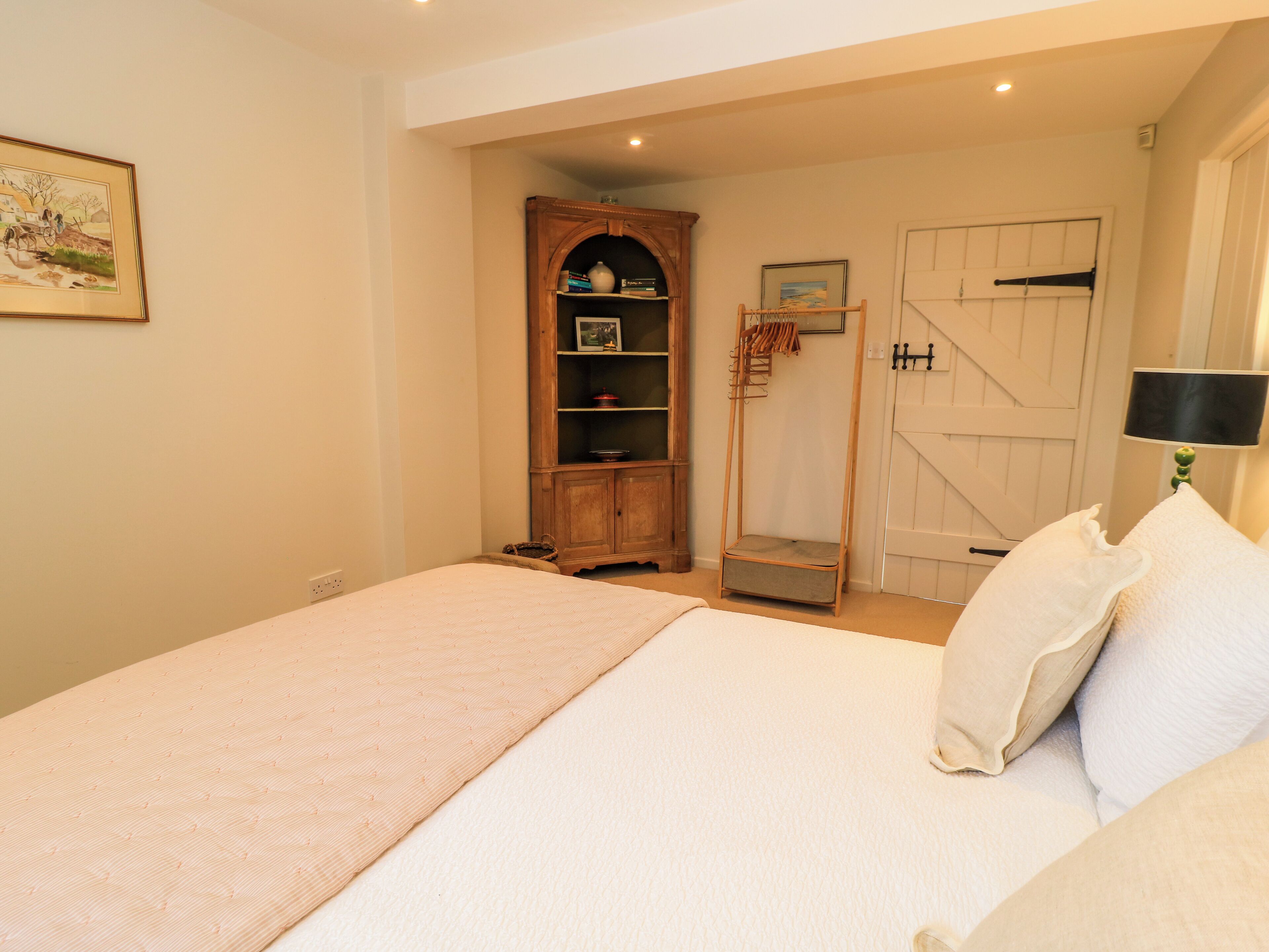 Une chambre à coucher avec un lit, une armoire en bois, une porte et une lampe.