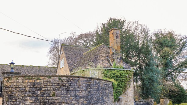 A stone building with a round tower, a small window, and a chimney. - The Elm Coach House (Chipping Norton)