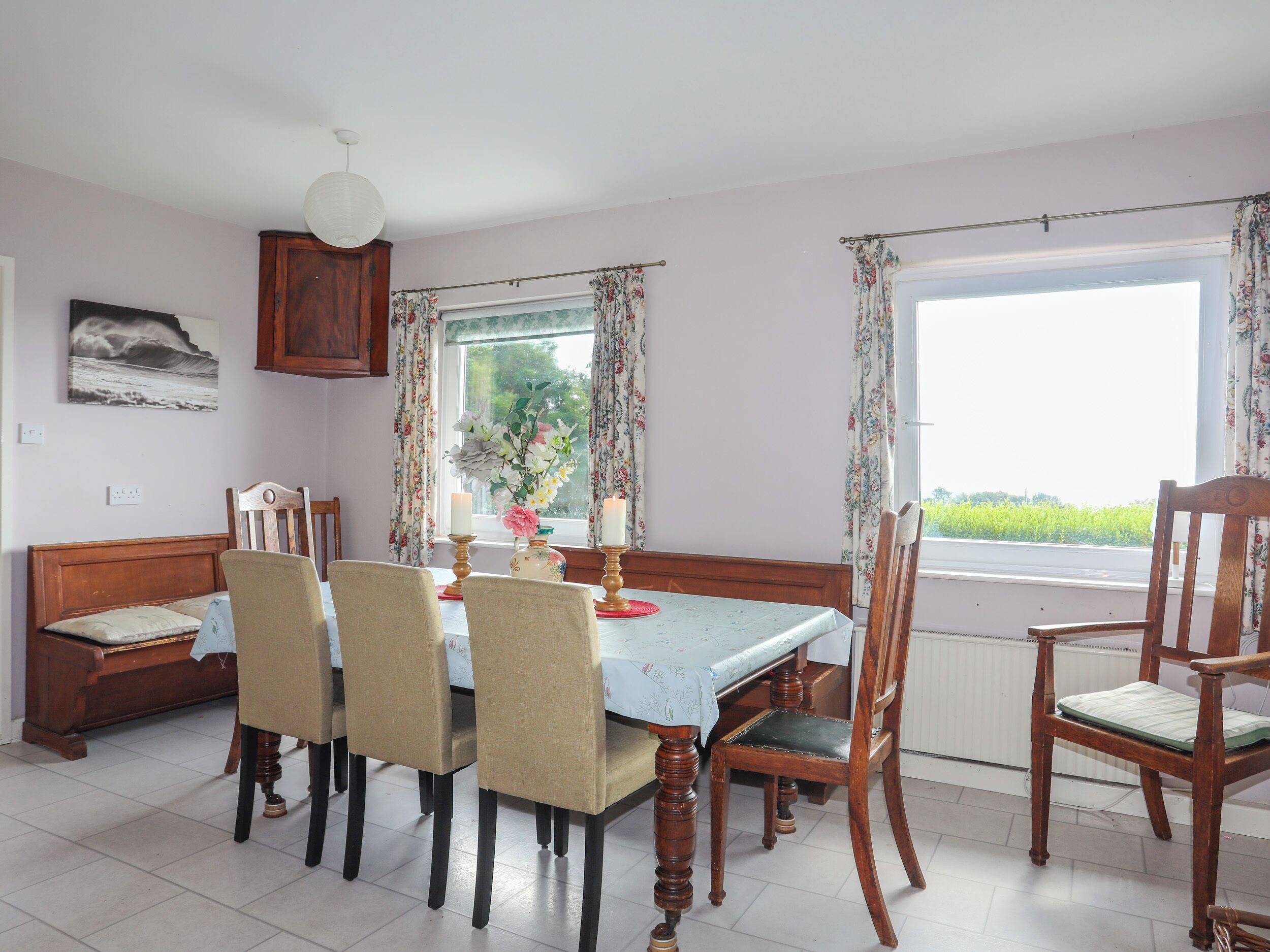 Une salle à manger avec une table dressée pour six personnes, entourée de chaises en bois dotées d’assises rembourrées.