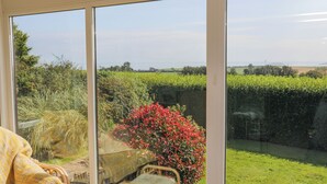 Una stanza con ampie finestre che si affaccia su un giardino e campi.