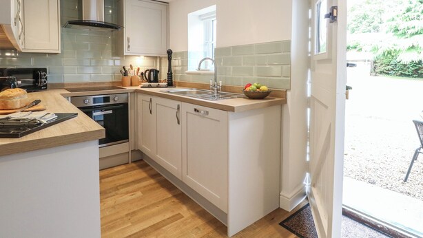 A modern kitchen with white cabinetry, a wooden countertop, and a built-in oven.