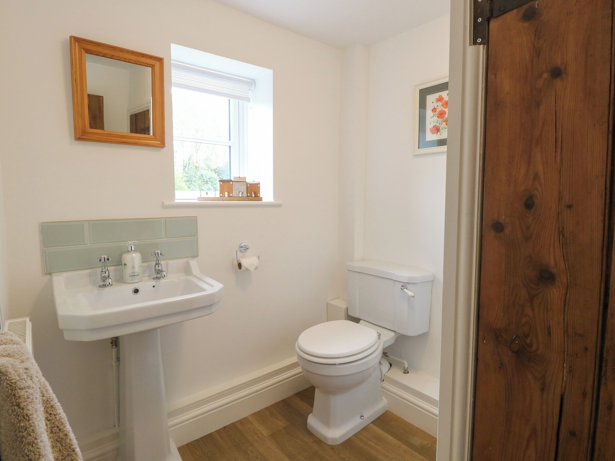 A bathroom with a white sink, a toilet, and a window with a view of greenery.