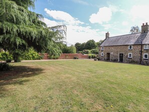 A stone building with a brick wall and a grassy courtyard.