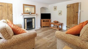 A living room with patterned sofas, a fireplace, a television, and wooden doors.