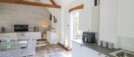Una cocina moderna con armarios blancos, horno empotrado y suelo de baldosas de piedra.