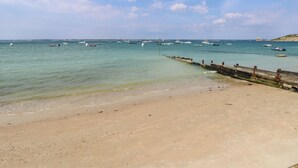 Una playa con barcos en el agua y una orilla arenosa.