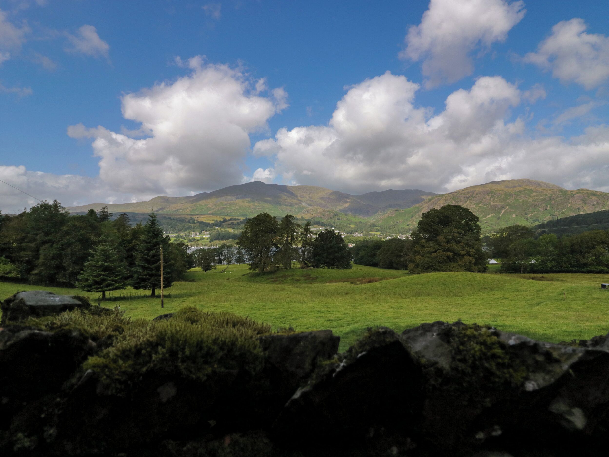 A rural landscape with rolling hills, a clear sky, and scattered clouds.