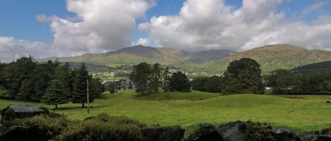 A rural landscape with rolling hills, a clear sky, and scattered clouds.