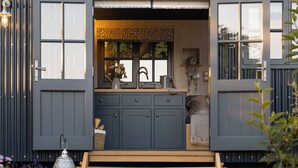 A compact, modern kitchen with a built-in sink, cabinets, and a window with a decorative valance.