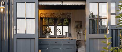 Una cocina compacta y moderna con un lavaplatos integrado, armarios y una ventana con un adorno decorativo.