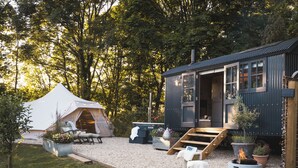 A cozy outdoor area with a tent, a small cabin, and a fire pit.