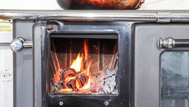 A wood-burning stove with visible flames inside. - Buttercup (Penzance)