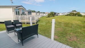 Eine Terrasse mit Gartenmöbeln, einem weißen Geländer und einem Rasen.