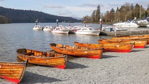 A marina with several wooden rowboats and a few motorboats docked at the pier. - Cosy Corner (Windermere)
