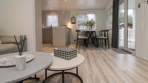 A modern living room with a round table, a sofa, and a kitchen in the background. - Cosy Corner (Windermere)