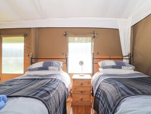 A bedroom with two beds, wooden nightstands, and a window with curtains. - Bluebell (Penzance)