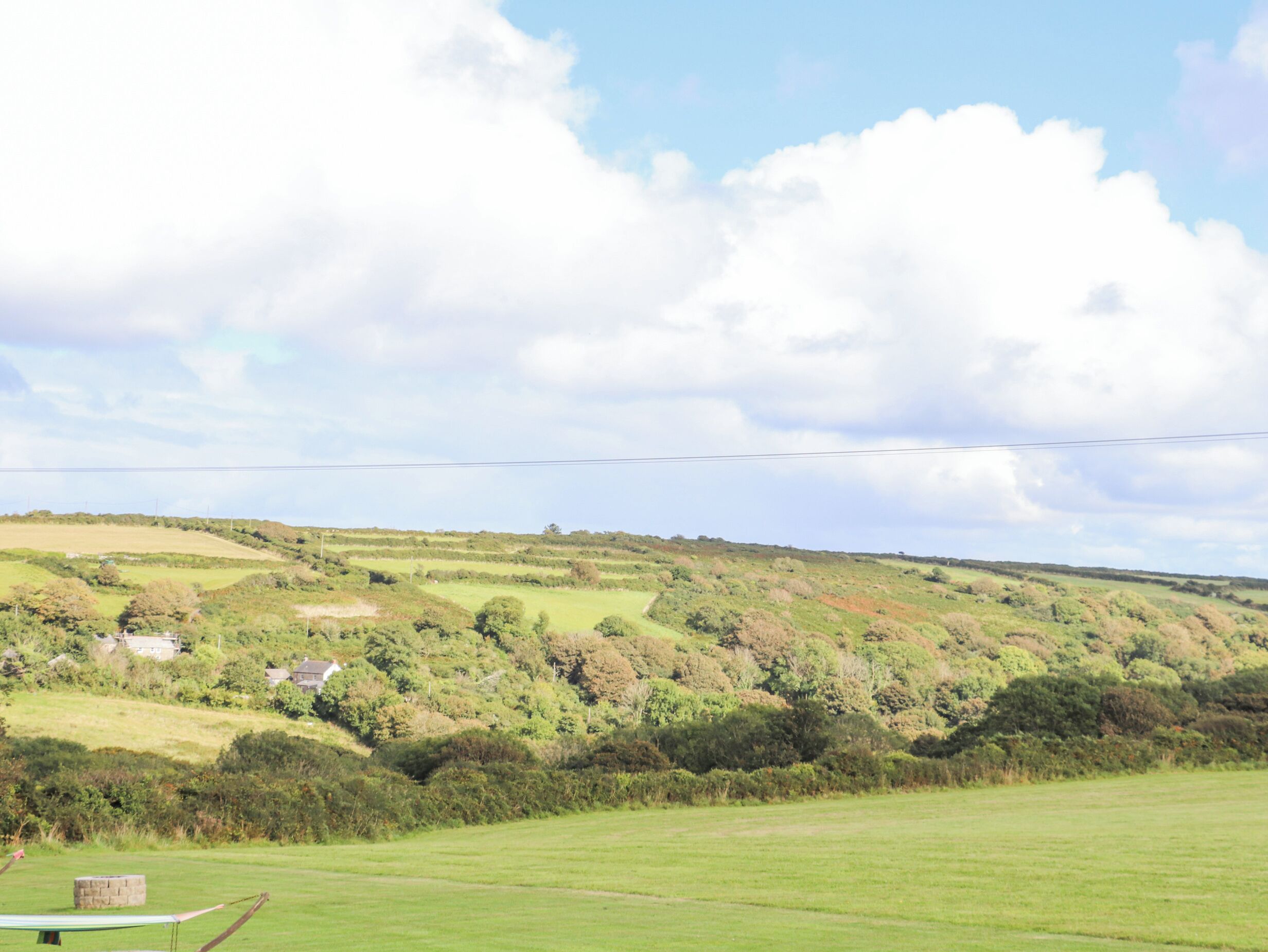 A rural landscape with rolling hills, scattered houses, and a clear sky.