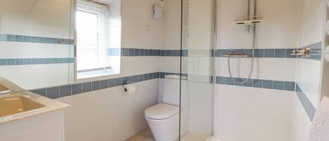A bathroom with a glass-enclosed shower, a toilet, and a sink.