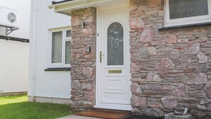 Une maison avec une façade en pierre, une porte blanche et un petit porche avec un paillasson.