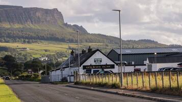 A rural road with a white building labeled "Ardlers Rest" and a mountain in the background.