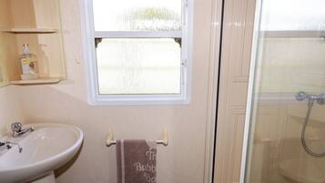 A bathroom with a sink, a window, and a shower.