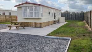 A mobile home with a patio, a picnic table, and a fenced yard. - Meric Stone Holiday Lets Caravan 1 (Limavady)