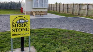 A sign for The Merc Stone Holiday Lets with a small building in the background. - Meric Stone Holiday Lets Caravan 1 (Limavady)