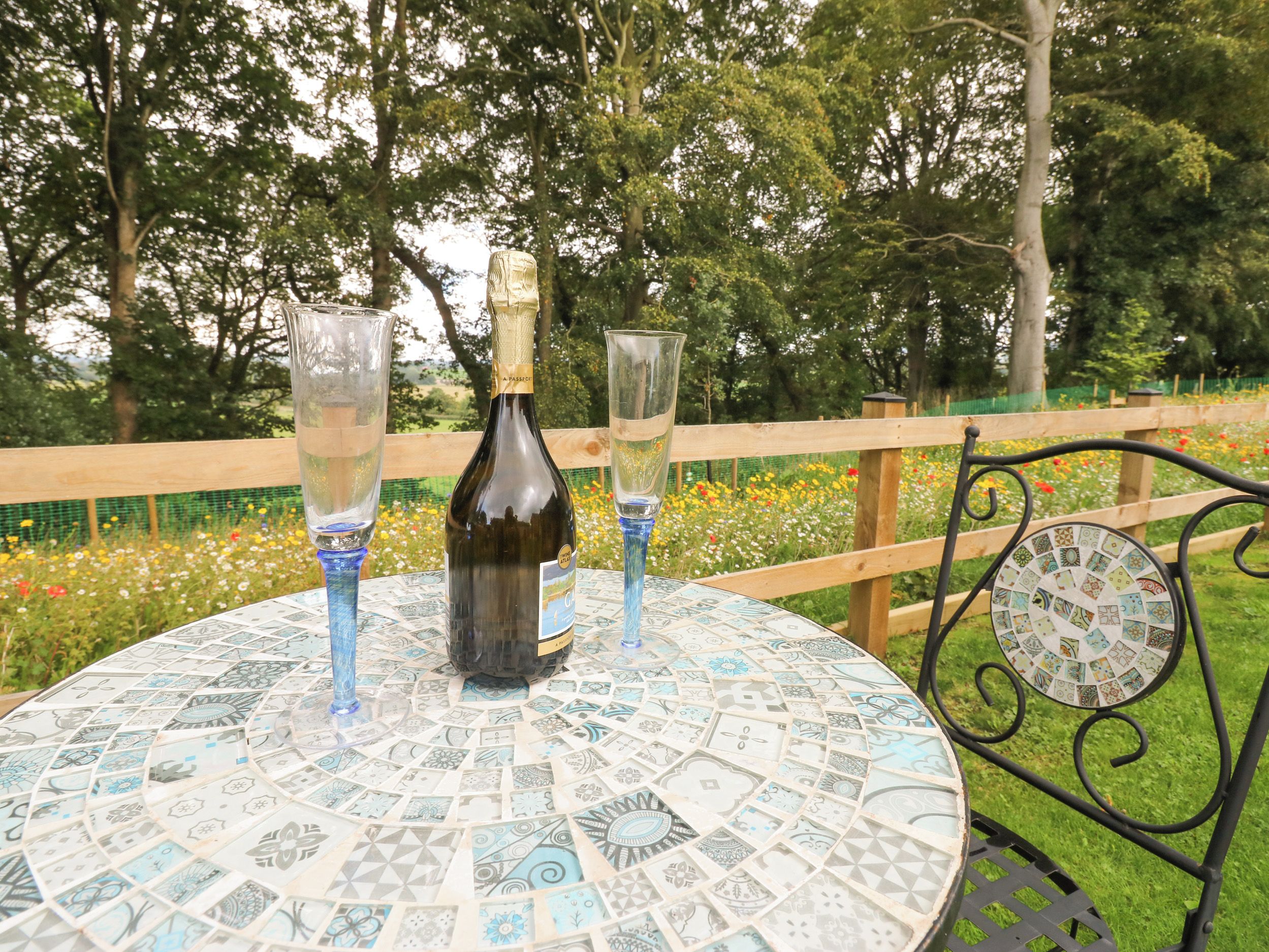 A round table with a patterned tabletop, a bottle, and two glasses.