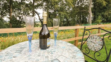 A round table with a patterned tabletop, a bottle, and two glasses.