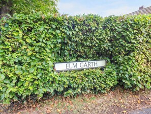 A hedge with a street sign reading "ELM GARTH". - The Nest (Carlisle)