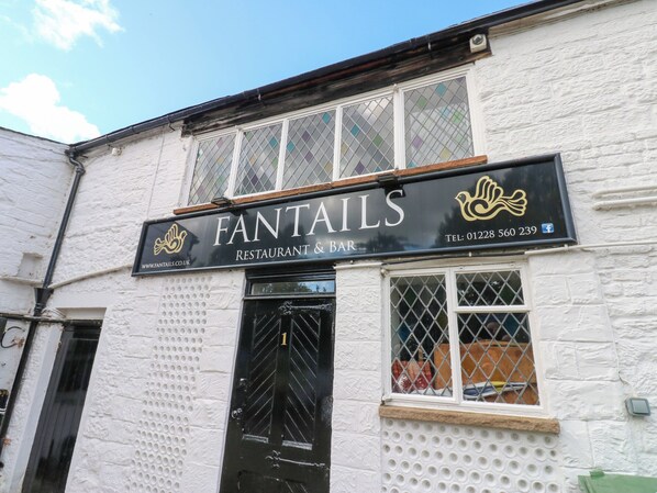 Un bâtiment sur lequel est apposée une enseigne indiquant « Fantails Restaurant & Bar » et sur laquelle figure un numéro de téléphone.