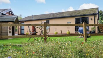 Un immobile residenziale con giardino recintato, patio e edificio con tetto in tegole.
