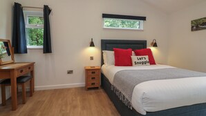 A bedroom with a bed, bedside tables, a desk, and a window with curtains. - Bay (Ilfracombe)