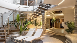 A spacious indoor area with a modern staircase, lounge chairs, and potted plants. - Coco Boutique Hotel & Spa  (Karpacz)