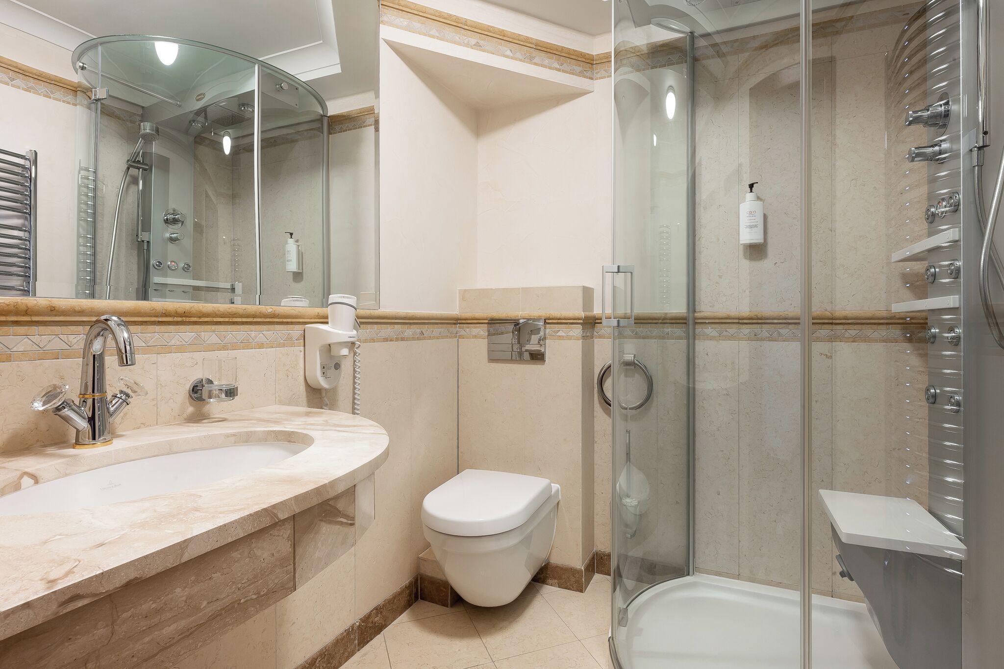 A bathroom with a glass-enclosed shower, a sink with a mirror, and a toilet.