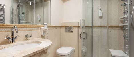 A bathroom with a glass-enclosed shower, a sink with a mirror, and a toilet.