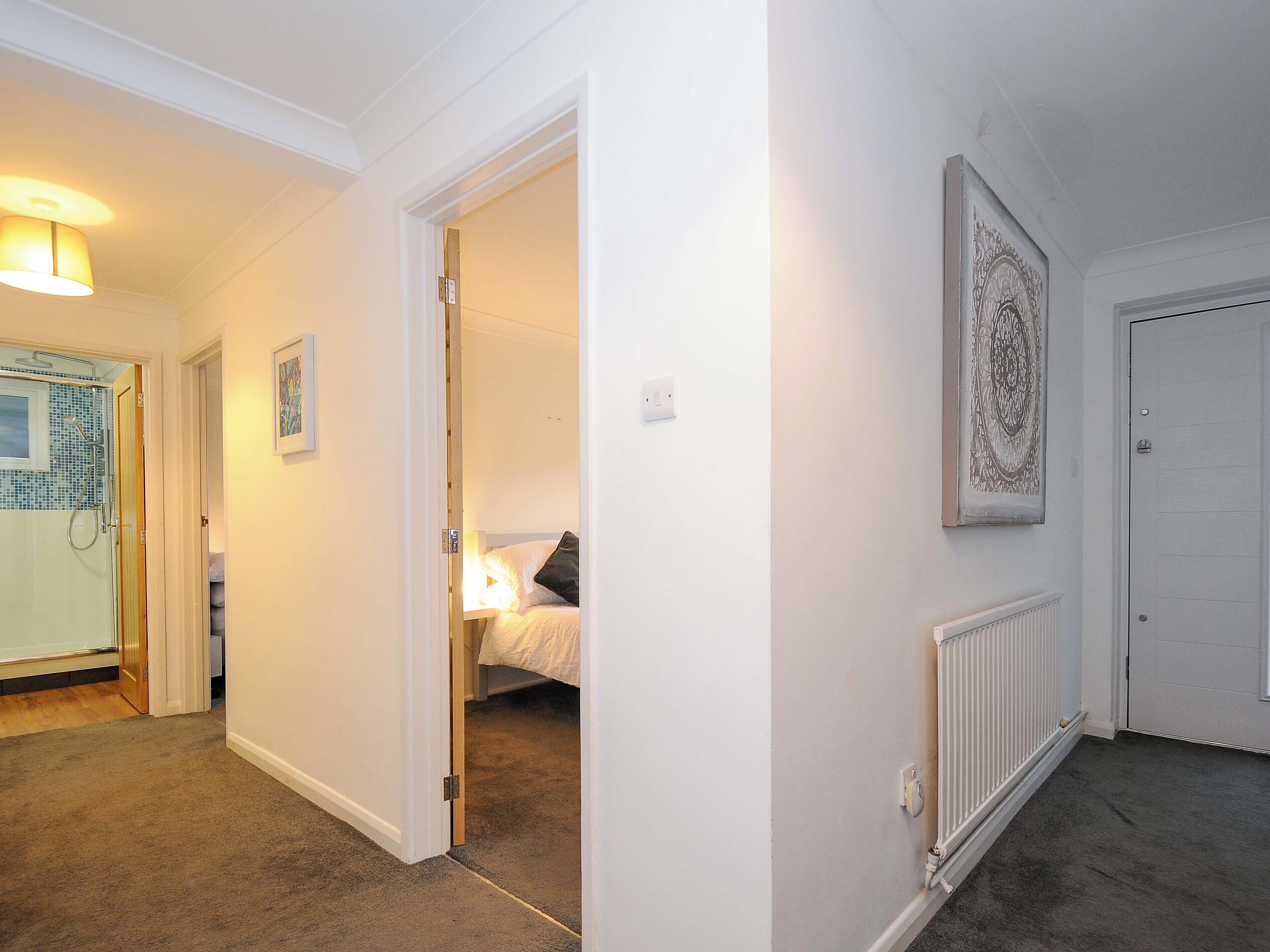 A hotel hallway with a bed, a radiator, and a door.